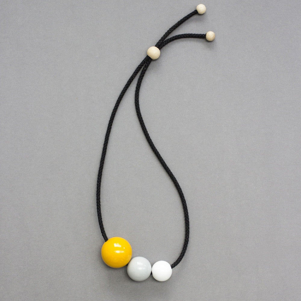 Bold, striking and fun statement necklace composed of three bright resin balls. Yellow, grey and white shiny resin balls on black cord. 
